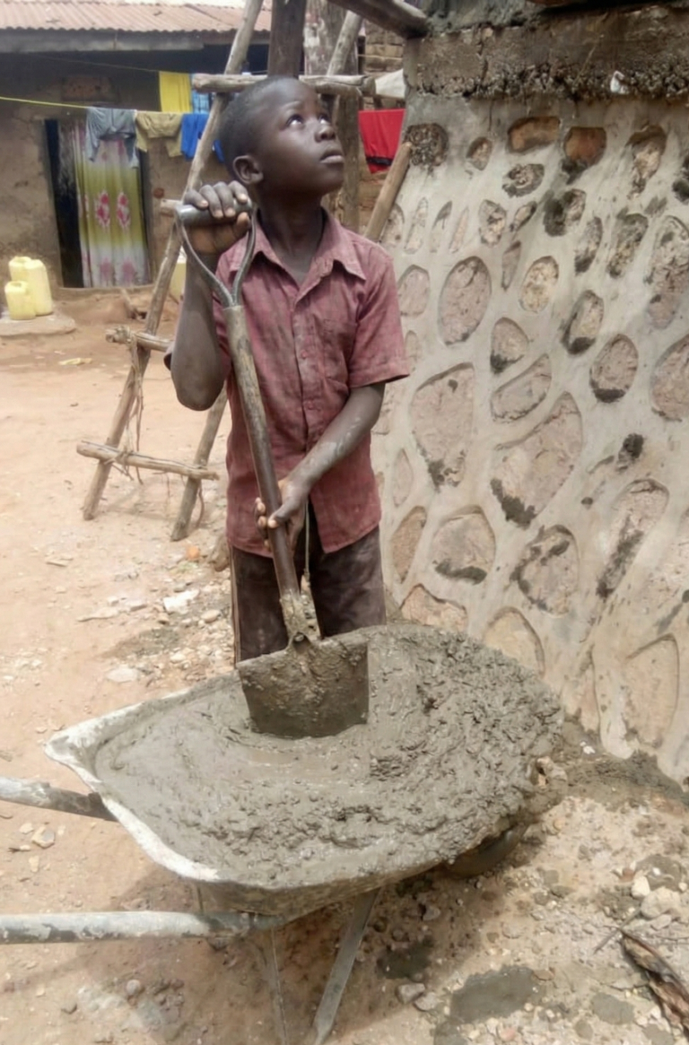 Close-up of a young child's dusty hands helping in building Wakiso.