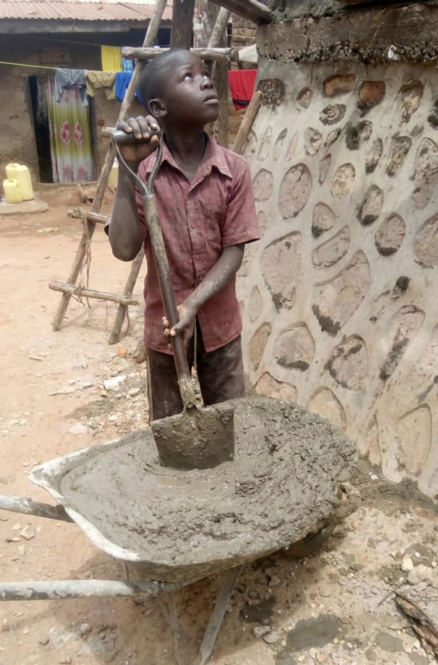 Close-up of a young child's dusty hands helping in building Wakiso.
